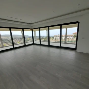 All Surfaces Flooring (1) Spacious room in Fort Mohave with floor-to-ceiling windows, gray tile flooring, and views of the balcony and landscape.
