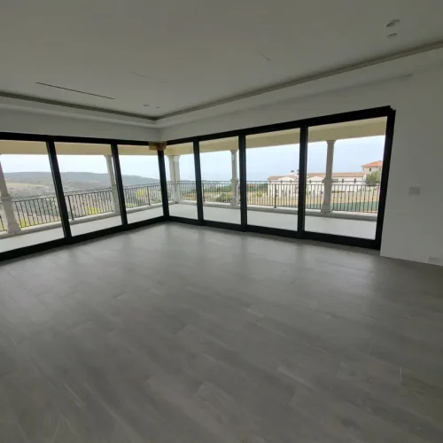 Spacious room in Fort Mohave with floor-to-ceiling windows, gray tile flooring, and views of the balcony and landscape.