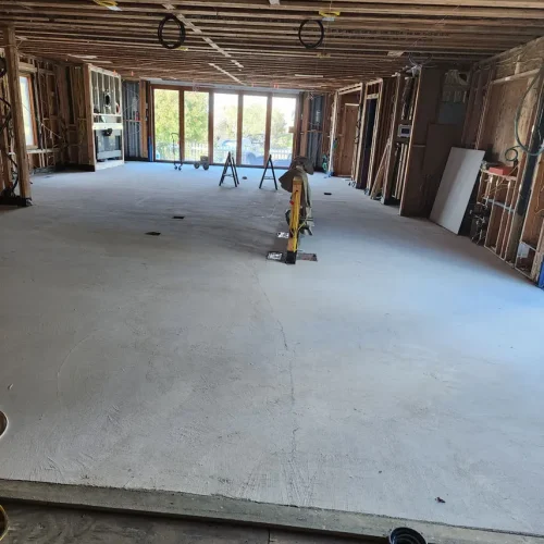A spacious room in Fort Mohave with exposed beams, unfinished walls, new concrete floor—ideal for a kitchen installation.